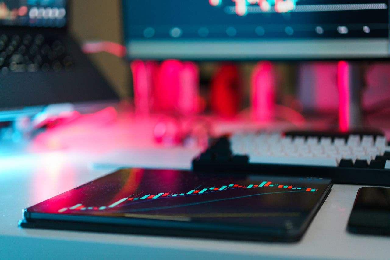 Laptop and tablet showing trading charts on a desk
